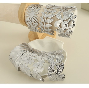 Detailed view of silver titanium steel open bangles with hollow floral and leaf patterns