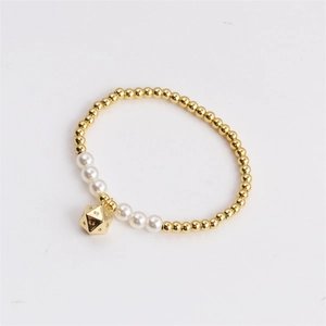 Elastic pearl bracelet with gold beads and a geometric pendant on a white surface