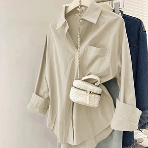 Détail d'un chemisier beige à boutons assorti à un mini sac matelassé blanc à chaîne