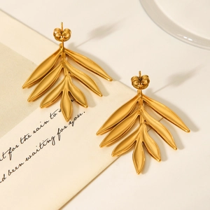 Macro shot of gold leaf earrings with 18K plating on a stylish white jewelry display card