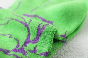 Détail macro de chaussettes de sport en tricot vert avec des motifs éclair violets