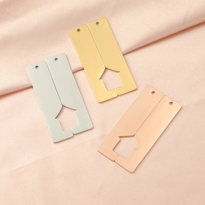 Detailed view of polished bar charms in gold, silver, and rose gold on pink silk