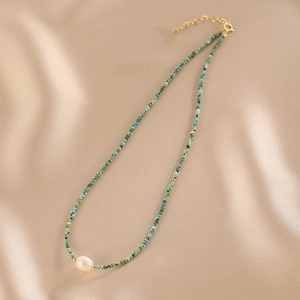 Detail of natural pearl and turquoise beaded necklace on luxury champagne silk fabric