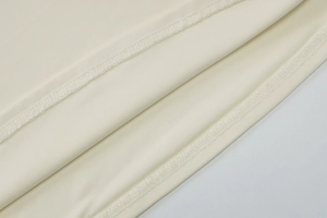 Detailed close-up of beige summer top fabric showing double stitching and fine texture
