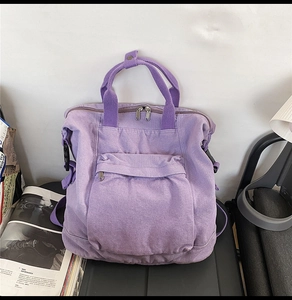 Detail of purple washed canvas backpack with dual top handles and front zipper pocket