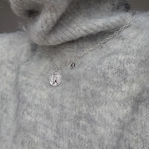 Macro detail of silver vintage queen portrait coin pendant on a knitted sweater
