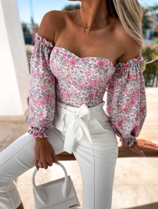 Detail of floral off-shoulder crop top paired with high-waisted white trousers and bow belt