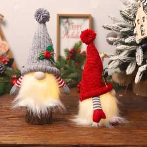 Set of two glowing Christmas gnomes with knitted hats and warm LED lights on wood