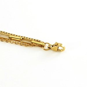 Macro shot of gold stainless steel lobster clasp and layered chain texture details
