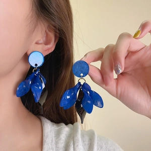 Close-up shot of artistic blue petal drop earrings featuring stylish retro round studs