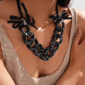 Detail of chunky black acrylic chain necklace with white spots and ribbon bow accents