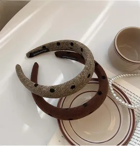 Detail of velvet polka dot headbands with handmade label on a vintage ceramic plate