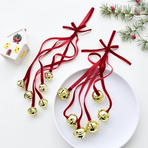 Golden Christmas bell hanging decoration with a red velvet ribbon on a festive background
