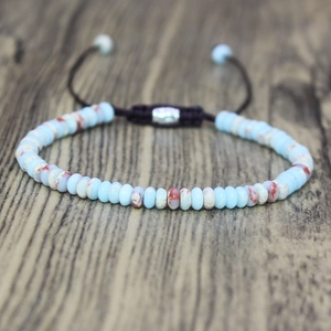 Bohemian 4mm stone bead woven bracelet with adjustable cord on natural wood surface