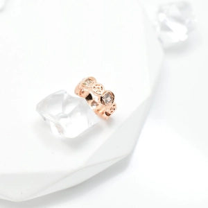 Hollow-out rose gold ring with inlaid crystals on white background with decorative props