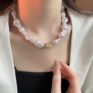 Gros plan du collier de perles baroques avec fermoir doré sur modèle pour un look chic