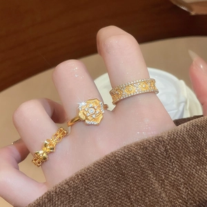 Close-up of gold flower and bow rings with sparkling diamonds on female hand
