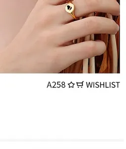 Detail of a minimalist gold-plated heart ring with black inlay on a hand with dry branch