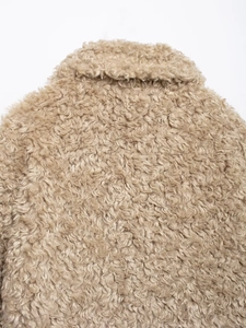 Close-up of thick beige faux fur texture and lapel stitching on the warm fleece jacket