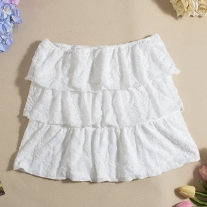 Detailed view of white three-layer lace tiered skirt on neutral floral background