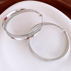 Gros plan détaillé de grandes créoles argentées polies miroir sur une assiette décorative