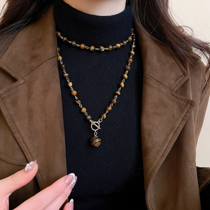 Dettaglio della collana a strati con perle occhio di tigre e chiusura OT dorata su modella