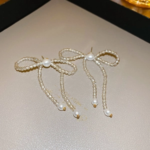 Dettaglio di orecchini eleganti a fiocco con cristalli e perle su un espositore grigio