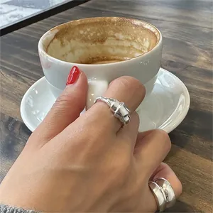 Close-up of irregular 925 sterling silver rings worn on hand over a dark wood background