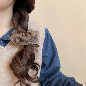 Detailed view of a brown knitted scrunchie with ruffle texture on wavy long hair