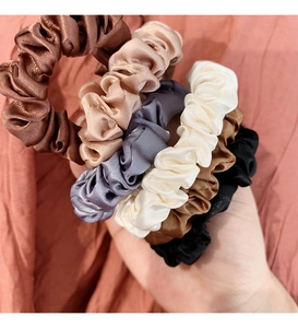 Dettaglio di 6 elastici per capelli in raso elegante con texture tipo seta neutra