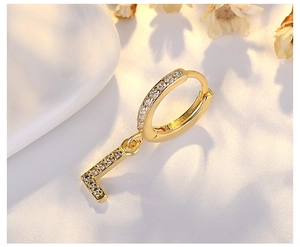 Macro shot of gold letter L earring pendant featuring micro-pave zircons on a white background