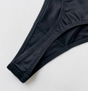 Detailed close-up of zigzag stitching on black high-stretch fitness thong underwear