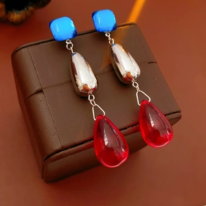Detailed shot of retro silver needle tassel earrings featuring blue studs and red pendants