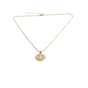 Detailed view of golden necklace with a zircon-encrusted religious medallion and clasp