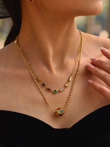 Gros plan détaillé de colliers en perles dorées avec pendentif boule en zircon coloré