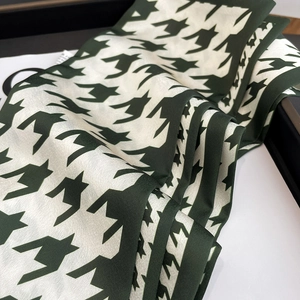 Detail of folded houndstooth silk scarf in dark green and white with a glossy texture