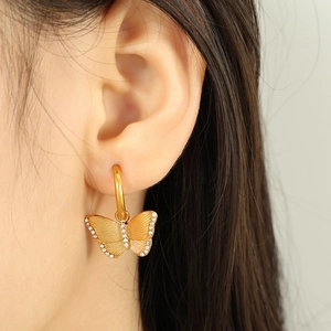Elegant gold butterfly earrings with shimmering zircons shown on ear for a delicate look