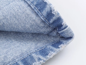 Vue détaillée de la texture du denim bleu avec bords effilochés et coutures contrastées