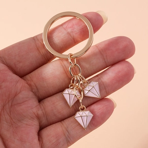 Detailed close-up of rose gold keychain with three pink diamond alloy pendants held by hand