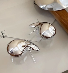 Macro shot of silver teardrop earrings with a high-shine mirrored finish on display