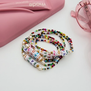 Detailed view of colorful beaded LOVE bracelets set with faux pearls and golden accents
