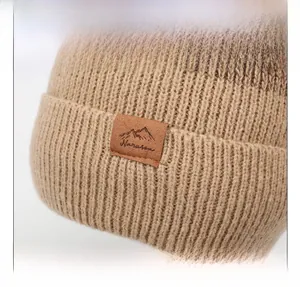 Dettaglio del berretto in maglia kaki con fodera in pile e patch logo in pelle goffrata