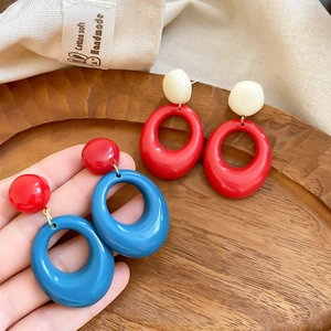 Détail de grandes boucles d'oreilles ovales en résine bleu et rouge pour vacances à la plage