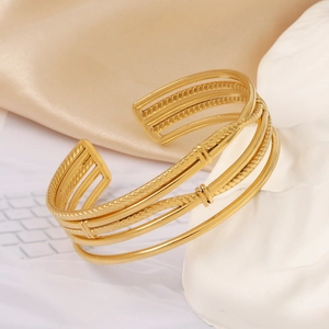 Detail of 18k gold plated stainless steel open cuff bracelet with braided textures
