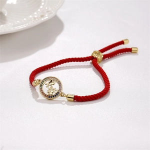 Détail d'un bracelet ajustable en corde rouge avec pendentif MAMA doré et zircons