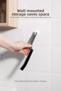 Aan de muur gemonteerde spleetborstel met ergonomische handgreep op een betegelde wand