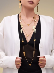 Close-up of gold-plated fishbone and heart necklace set worn by a model in soft light
