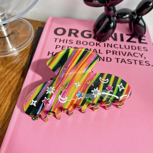 Detail of large rainbow acetate hair claw clip with star and moon glitter decorations