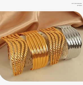 Detailed view of wide gold and silver multi-layer cuff bangles with woven metal textures