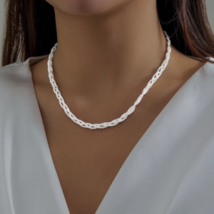 Detailed view of layered silver-toned twisted chain necklace worn on a clean white V-neck top
